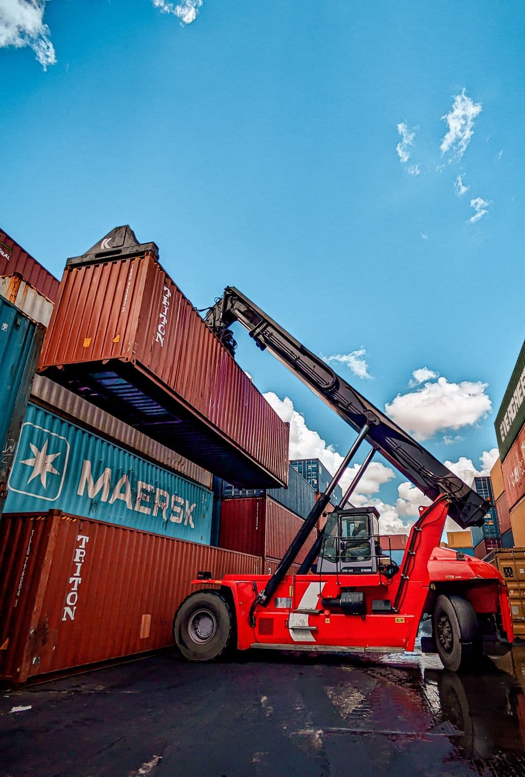 Reach stacker lifting a shipping container at a port yard — container handling and freight forwarding training