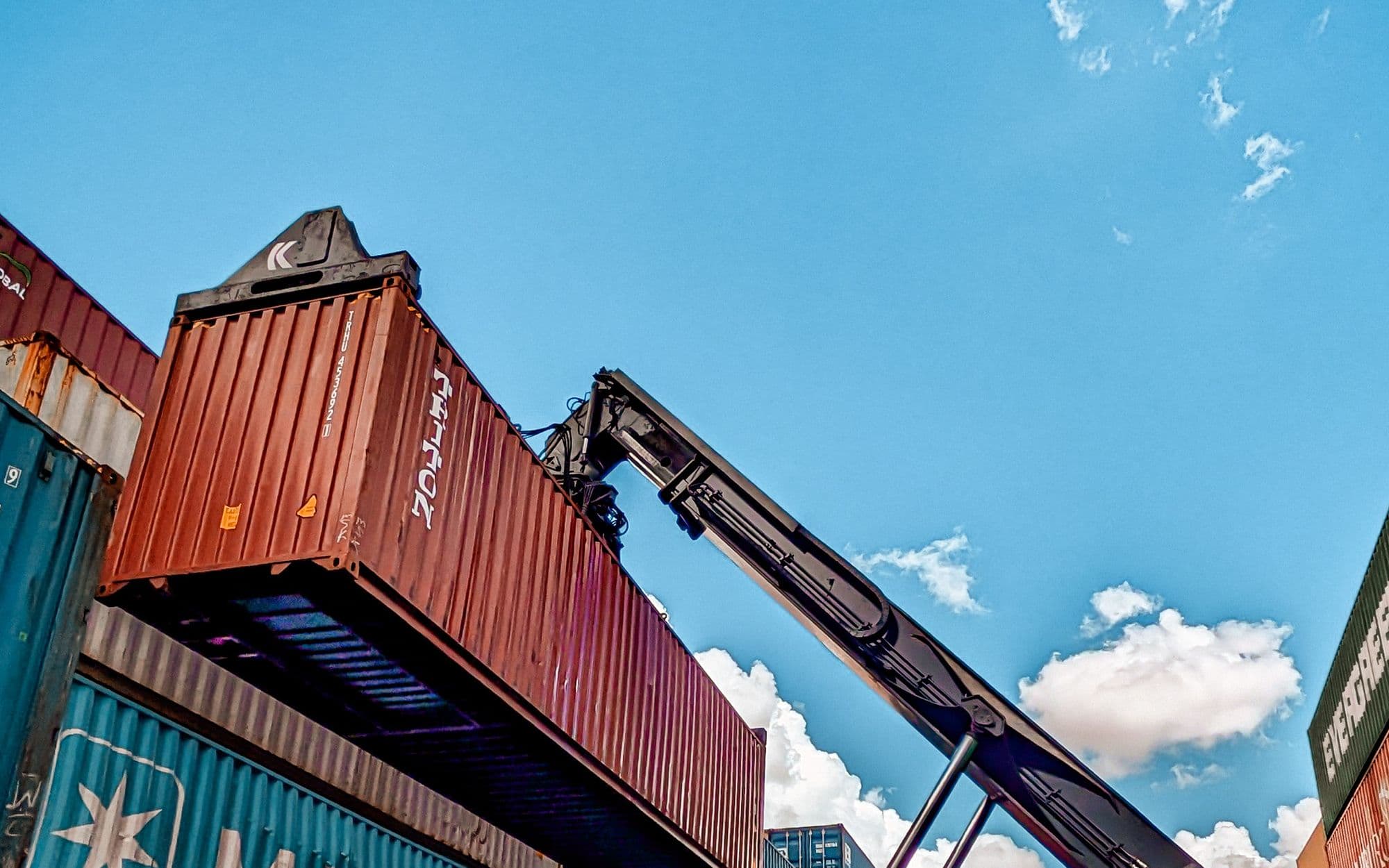 Reach stacker lifting a shipping container at a port yard — container handling and freight forwarding training